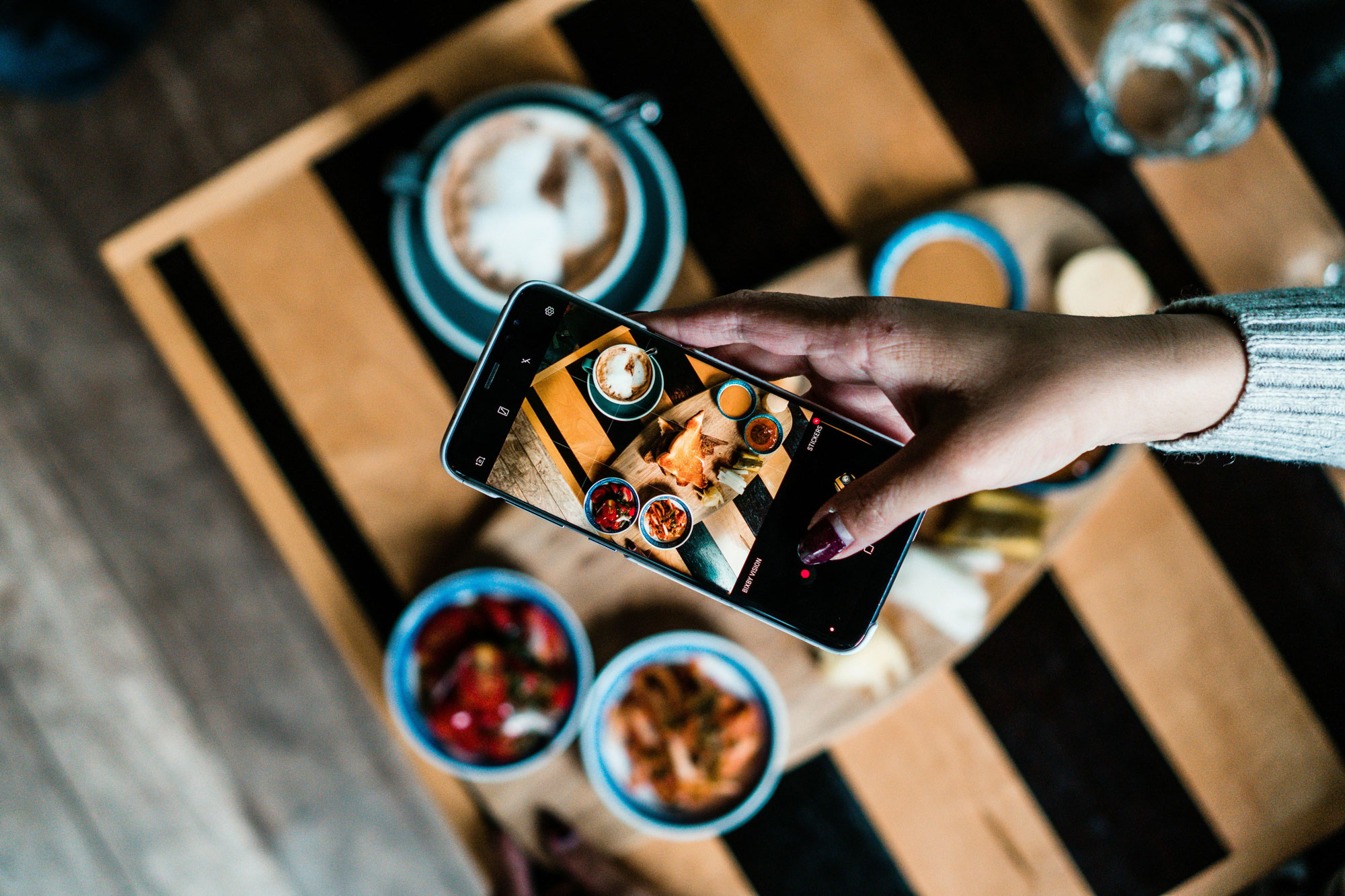 Person fotografiert angerichtete Speisen mit einem Smartphone