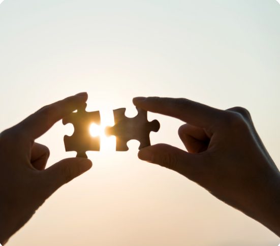 Zwei Hände fügen Puzzleteile zusammen